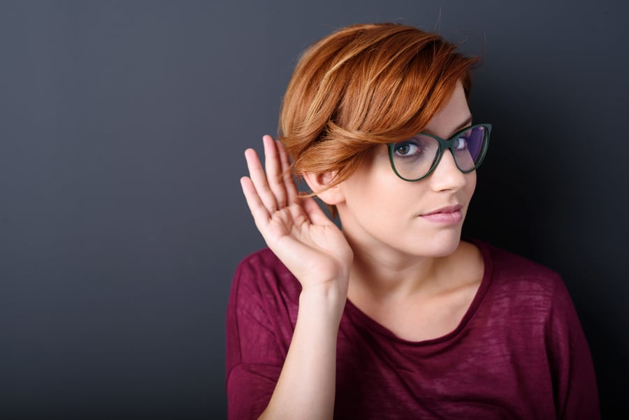Young woman with a hearing disorder or hearing loss cupping her hand behind her ear with her head turned aside to try and amplify and channel the available sound to her ear drum-1
